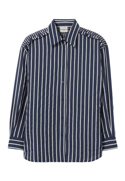 Camisa de botones azul marino con rayas verticales blancas, con acentos texturizados en los hombros y un cuello clásico. Tejido suave, mangas largas.