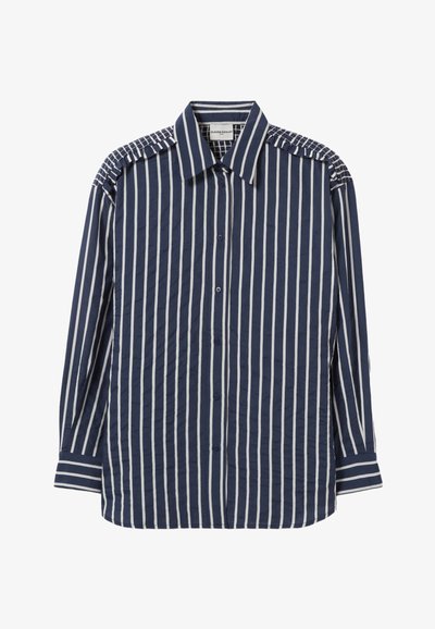 Chemise bleu marine à boutons avec des rayures verticales blanches, présentant des accents texturés aux épaules et un col classique. Tissu lisse, manches longues.