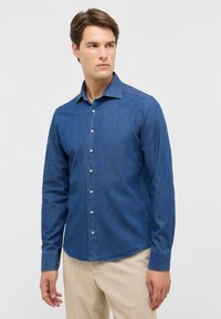 Donkerblauwe spijkerblouse met lange mouwen en een puntige kraag, voorzien van knoopsluitingen en een gladde textuur. Getailleerde pasvorm.