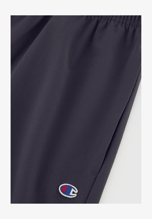 Pantalones cortos deportivos de color gris oscuro, confeccionados en una tela suave, con una cintura elástica y un pequeño logotipo bordado en azul, rojo y blanco.