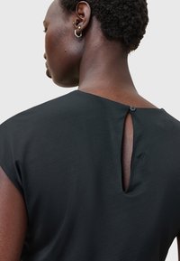 Schwarzes Oberteil mit einem Rückenschlitzdesign und Knopfverschluss, kurzen Ärmeln und einer glatten Textur. Fokus auf minimalistische Designdetails.