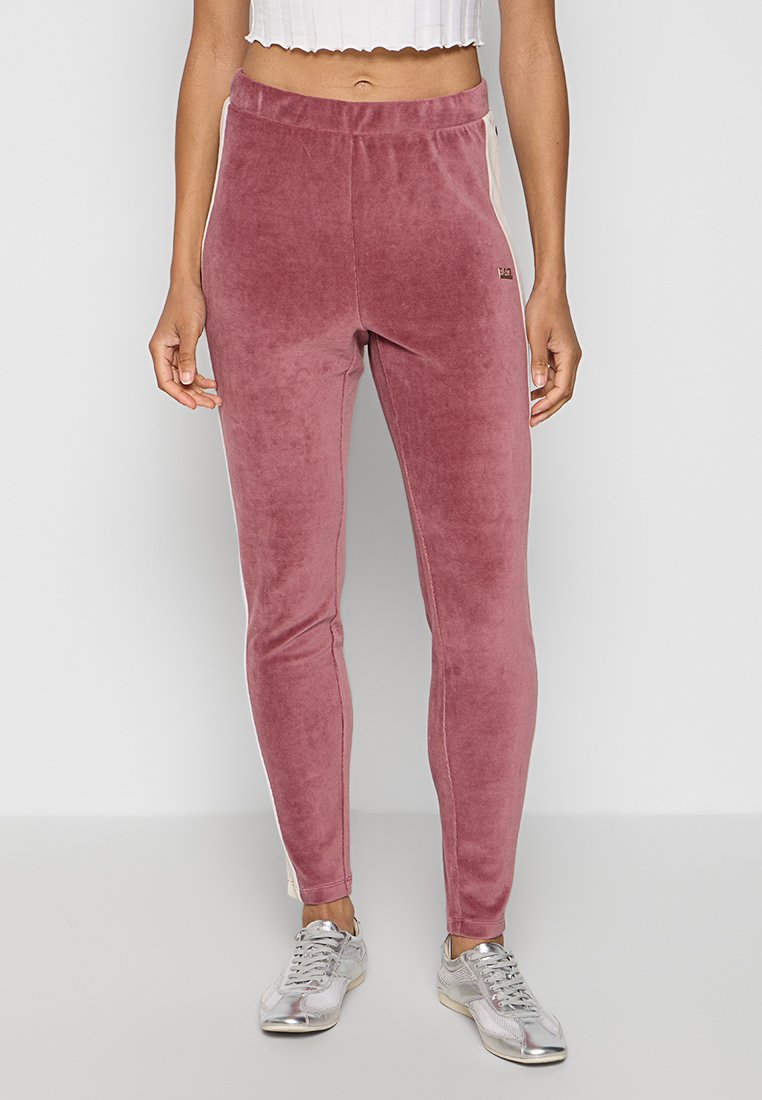 Welurowe dresy w kolorze zgaszonego różu o dopasowanym kroju, z elastycznym pasem i kontrastowymi panelami bocznymi. Posiadają mały detal z logo w okolicy pasa.