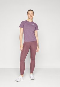 Tenue de sport composée d'un t-shirt ajusté en jersey violet et de leggings taille haute assortis, complétée par des baskets blanches.