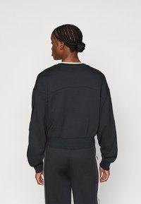 Μαύρο υπερμεγέθες φούτερ με ριμπ τελείωμα, στρογγυλή λαιμόκοψη και ελαφρώς χαμηλωμένους ώμους, κατασκευασμένο από μαλακό ύφασμα για άνεση.