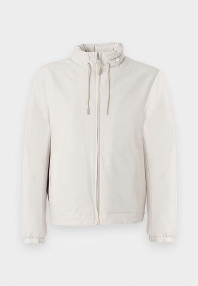 Lyse beige jakke lavet af blødt stof, med lynlås lukning, justerbare snore i kraven og elastiske manchetter.