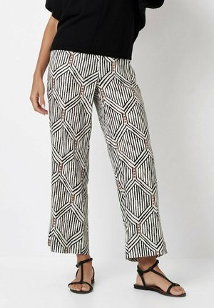Musterhose mit einem geometrischen Schwarz-Weiß-Design, das Hexagone und vertikale Streifen zeigt, aus leichtem Stoff gefertigt.