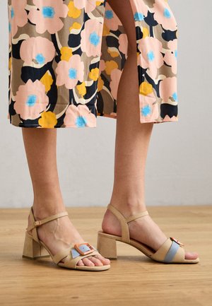 Beżowe sandały z grubym obcasem, z pomarańczową klamrą i jasnoniebieskim paskiem. Gładka tekstura i otwarty nosek.