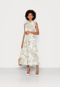 Abito midi senza maniche floreale con collo a camicia, tessuto crema chiaro con motivi botanici verdi, vita cinchata e gonna fluida.