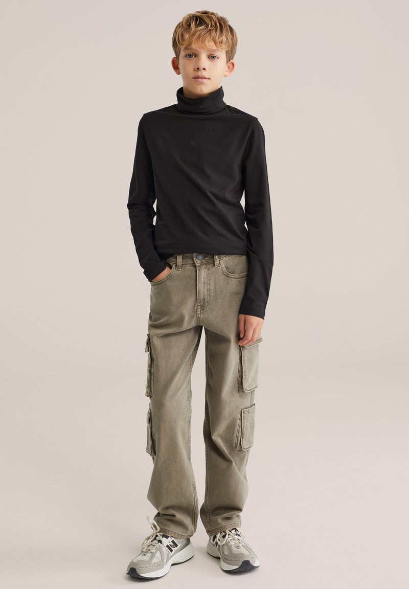 Svart långärmad polotröja, olivfärgade cargobyxor med flera fickor och grå sneakers med mesh- och solida detaljer. Enfärgad bakgrund.