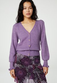 Paarse gebreide cardigan met een V-hals, gouden knoopsluitingen en opgeblazen mouwen. De stof lijkt zacht en gestructureerd.