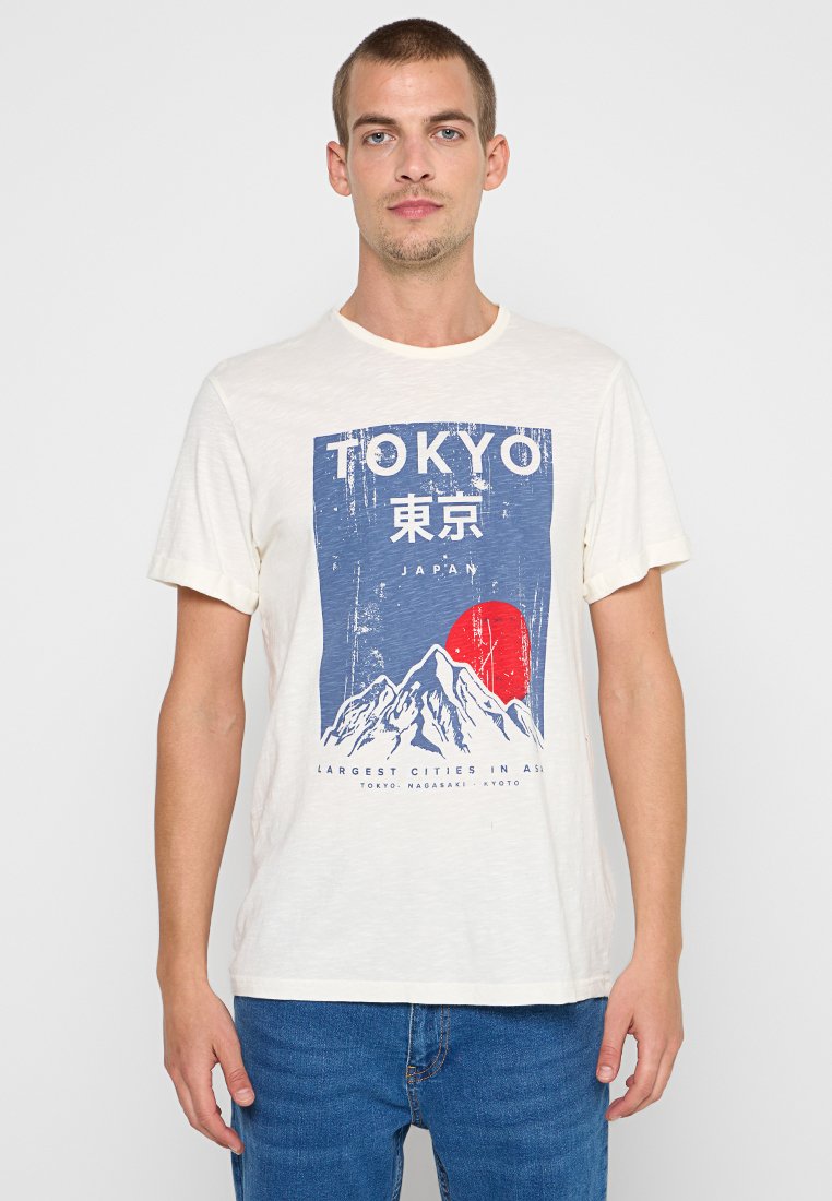 Bawełniana koszulka w kolorze off-white z niebieskim i czerwonym nadrukiem graficznym przedstawiającym góry oraz napisem "TOKYO". Krótkie rękawy, klasyczny dekolt.