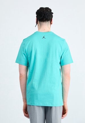 Turkusowa bawełniana koszulka z czarnym logo Jordana na plecach. Krótkie rękawy i okrągły dekolt. Gładka faktura i luźny krój.