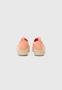 Espadrilles en toile corail avec une semelle en jute texturé, dotées d'un design à enfiler et d'une languette à l'arrière pour un enfilage facile.