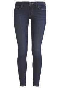 Jeans ajustados de denim índigo oscuro con una textura suave, que cuentan con un cierre frontal de botón y cinco bolsillos, incluyendo dos bolsillos traseros.