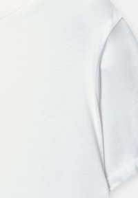 Bela bombažna majica s kratkimi rokavi, ki prikazuje zložen rokav in gladko teksturo tkanine.