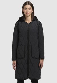 Cappotto lungo trapuntato nero con zip frontale, cappuccio e due grandi tasche. Texture liscia con un motivo a rombi e piping a contrasto.