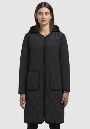 Manteau long matelassé noir avec fermeture éclair à l'avant, capuche et deux grandes poches. Texture lisse avec un motif en losange et un piping contrasté.