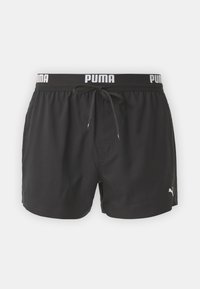 Svarte svømmebukser med elastisk midje, med en hvit "PUMA" logo, snor og en sidelomme. Glatt stofftekstur.