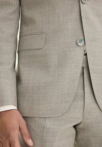Giacca da suit grigia chiara con una sottile texture, dotata di revers a punta, taschino sul petto, chiusura con due bottoni e bottoni a contrasto.