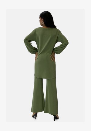 Olivengrünes Outfit mit einem langen, lockeren Oberteil mit Trompetenärmeln und weit geschnittenen Hosen, hergestellt aus einem glatten, leichten Stoff.