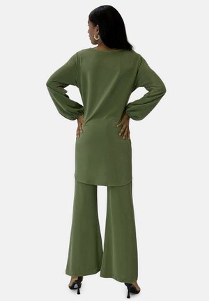 Olive green outfit with a loose-fit top and wide-leg trousers, featuring long balloon sleeves and smooth fabric, worn with high heels.