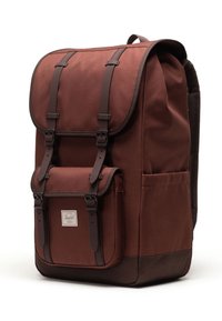 Zaino rettangolare marrone con patta e tasca frontale assicurate da cinturini in fibbia marrone scuro, tasca laterale e pannello posteriore in rete imbottita.