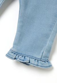 Helle blaujeans mit einem Rüschensaum, glatter Textur und kontrastierenden Nähten entlang der Kanten.