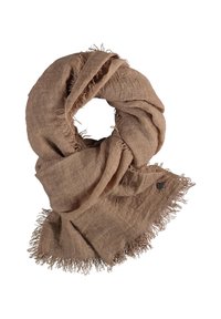 Écharpe texturée marron clair avec bords effilochés, roulée librement, et une petite étiquette ronde noire attachée à un coin sur un fond blanc.