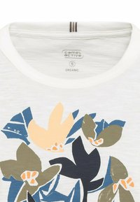 Witte biologische katoenen t-shirt met een kleurrijke bloemenprint in blauwe, groene en perzik tinten, met een ronde halslijn en contrasterende stiksels.