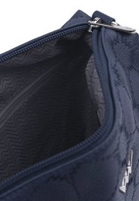 Námorně modrá zipová taška vyrobená z texturovaného materiálu, s vnitřkem se zigzagovým vzorem. Obsahuje stříbrné kování.