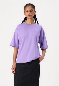 Tricou din bumbac violet cu mâneci scurte și largi și gât rotund. Are un logo alb Puma pe piept. Este asortat cu o fustă neagră.