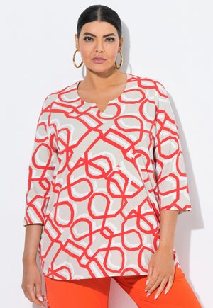 Lunga tunica con un motivo geometrico rosso e beige, scollo a V, maniche a tre quarti e vestibilità morbida. Tessuto dalla consistenza soffice.
