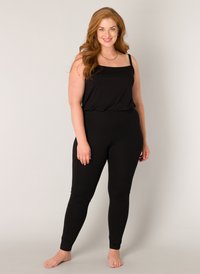 Zwart tanktop en legging set in een gladde stof. De tanktop heeft dunne bandjes en een ontspannen pasvorm; de leggings zijn aansluitend met enkelboorden.