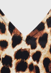 Látkový vzor v leopardím style s nízkým výstřihem do V. Hlavními farbami sú béžová, hnedá a čierna. V prednej časti je zdobené cik-cakovým švom pozdĺž výstrihu.