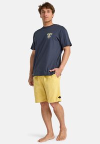 Tricou din bumbac de culoare albastră închisă cu un grafic colorat pe piept, combinat cu pantaloni scurți din catifea cu o etichetă logo neagră.