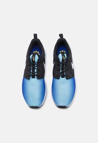 Sport shoes featuring a gradient blue upper, black laces, and a white sole. Notable gold accents on the tongue and logo detail.