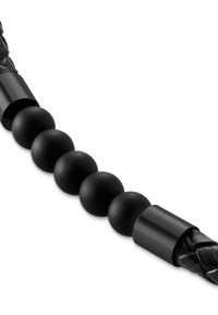 Sort flettet reim med glatte svarte runde perler og elegante sylindriske detaljer. En kombinasjon av teksturer og former i monokrome toner.