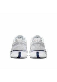 Weiße Sportschuhe mit einer strukturierten Oberseite, ausgestattet mit einem marineblauen Akzentstreifen und Logo an der Ferse. Rundliche Form und flache Sohle.