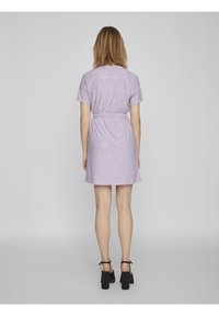 Lilac short-sleeve dress with a belt, featuring eyelet detailing and a slightly flared hem. Paired with black block-heeled shoes.