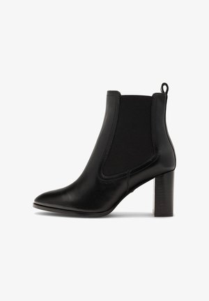 Fekete bőrből készült bokacsizma, hegyes orral, rugalmas oldalsó panelekkel és fa blokk sarokkal. Sima felületű és minimális díszítéssel.