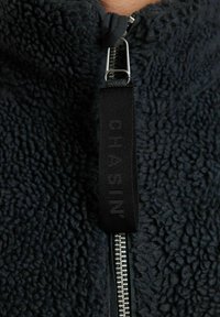 Giacca in pile nera con zip e superficie testurizzata. Include un'etichetta in tessuto nera con lettering in rilievo al collo.