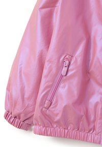 Ärmel einer pinken glänzenden Jacke mit elastischem Bund und geschlossenem Reißverschluss auf einem glatten Stoffhintergrund.