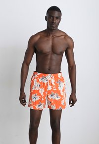 Pantaloni de înot portocalie strălucitoare, cu un model floral în nuanțe de albastru și alb, având o talie elastică și șnur pentru ajustare.
