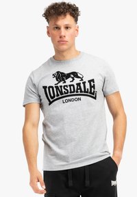 Pilkas medvilnės marškinėliai su juodu liūto grafiku ir tekstu "Lonsdale London". Trumpomis rankovėmis ir apvali iškirpte. Lygus paviršius.