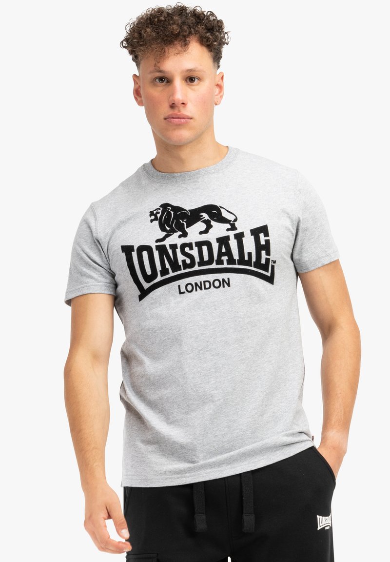 Pilkas medvilnės marškinėliai su juodu liūto grafiku ir tekstu "Lonsdale London". Trumpomis rankovėmis ir apvali iškirpte. Lygus paviršius.