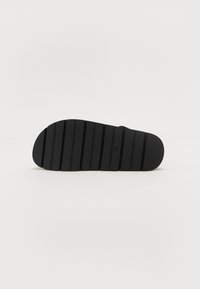 Suela de zapato negra con estrías horizontales, borde redondeado y textura suave. Diseño minimalista sin marcas visibles ni detalles adicionales.