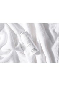 Flacone pompa bianco di OSKIA Renaissance Gel Cleanser su un morbido asciugamano bianco, con una superficie testurizzata e un design minimalista.