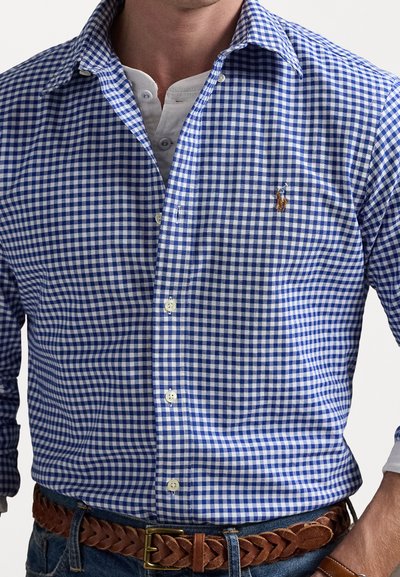 Blauwe en witte gingham ruitjesoverhemd met een button-down kraag en een klein logo op de borst. Draag het over een witte henley en in combinatie met een bruine riem.