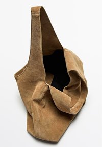 Borsa a spalla in suede marrone con un'apertura ampia, texture morbida e una sola tracolla. L'interno è nero e non ci sono ulteriori scomparti visibili.