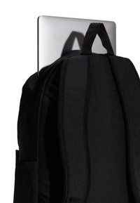 Svart ryggsäck med vadderad baksida, innehållande en silverfärgad laptop. Har en sidoficka och förstärkta remmar för hållbarhet.